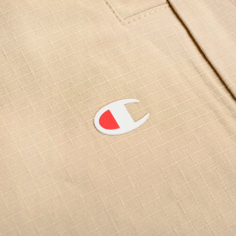 Zbliżenie na logo na beżowych krótkich spodenkach Champion