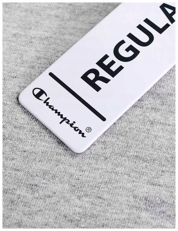 Zbliżenie na czarne metkę na szarej koszulce damskiej Champion