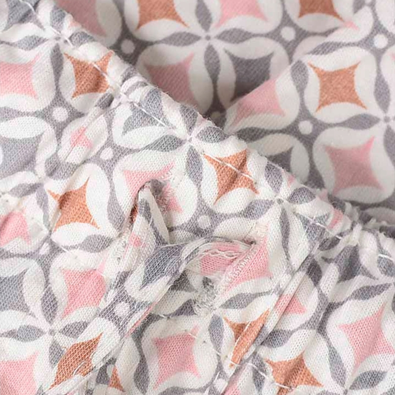 Zbliżenie na wiązanie w pasie spodni z geometrycznym wzorem w różowo-szare kolory.