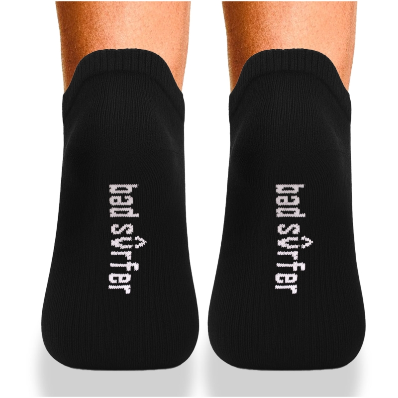 Widok z góry na czarne stopki Bad Surfer założone na stopy, z logo na spodzie