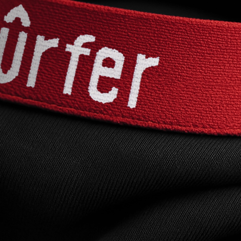 Zbliżenie na czerwoną gumę bokserek Bad Surfer z białym haftem i czarnym materiałem