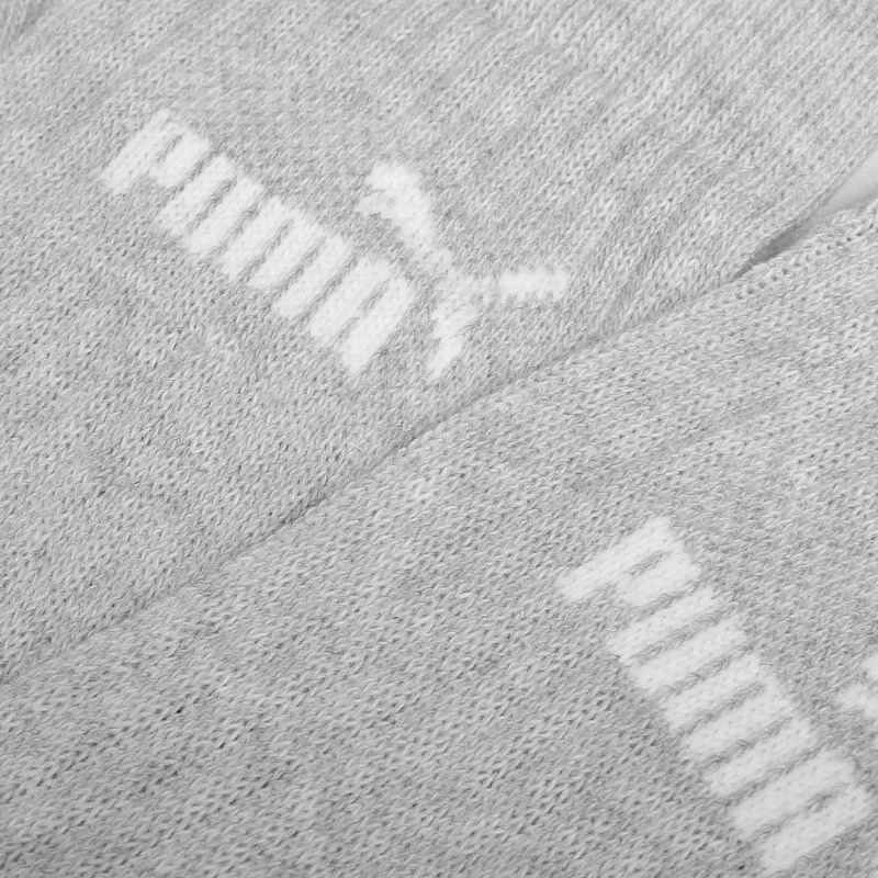 Zbliżenie na strukturę materiału i logo Puma na szarej skarpetce.