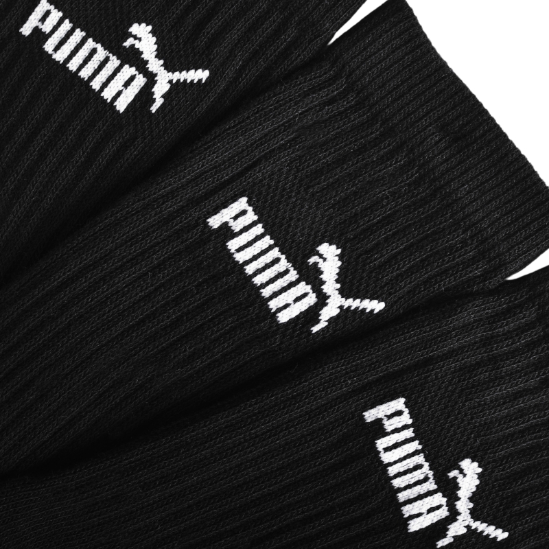 Trzy czarne skarpetki Puma rozłożone obok siebie z białym logo.