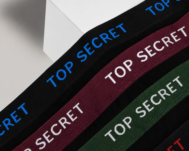 Zbliżenie na kolorowe gumy i napisy Top Secret na czarnych bokserkach