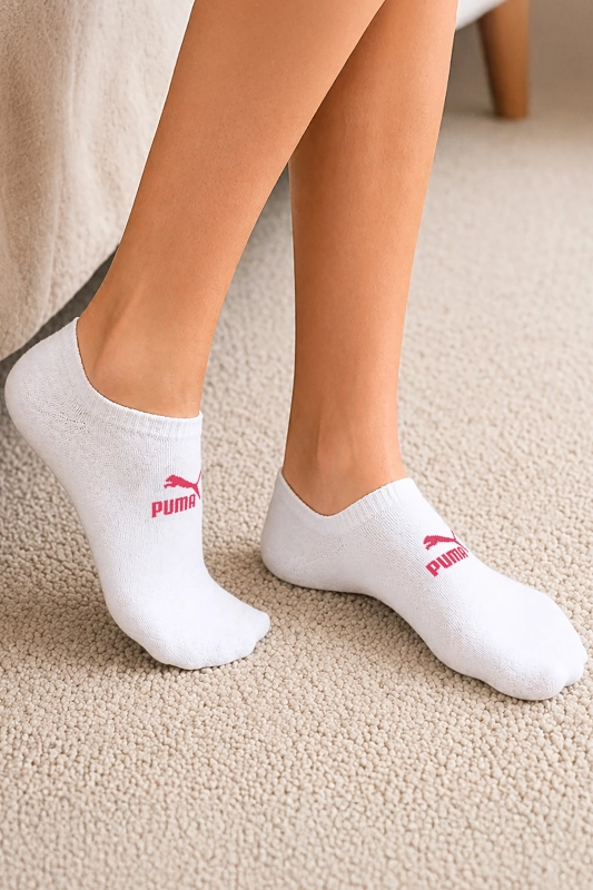 Białe stopki PUMA z różowym logo założone na stopy