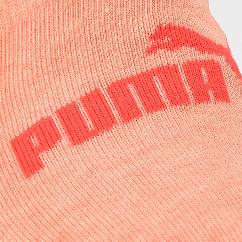 Zbliżenie czerwonego logo PUMA na brzoskwiniowej dzianinie