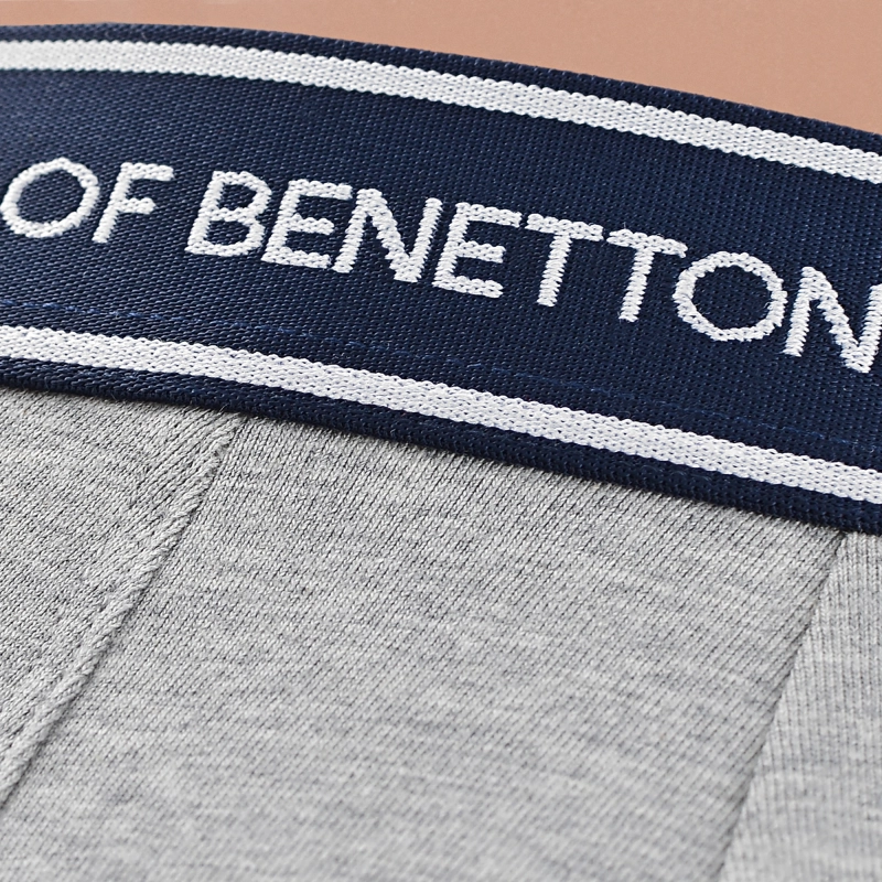 Zbliżenie na gumę z napisem United Colors of Benetton i szary materiał